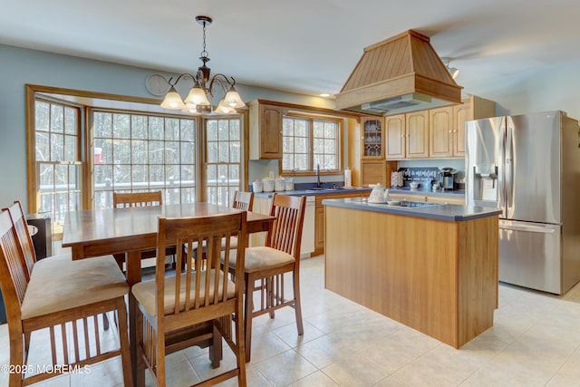 kitchen featuring a notable chandelier, a center island, hanging light fixtures, stainless steel refrigerator with ice dispenser, and sink