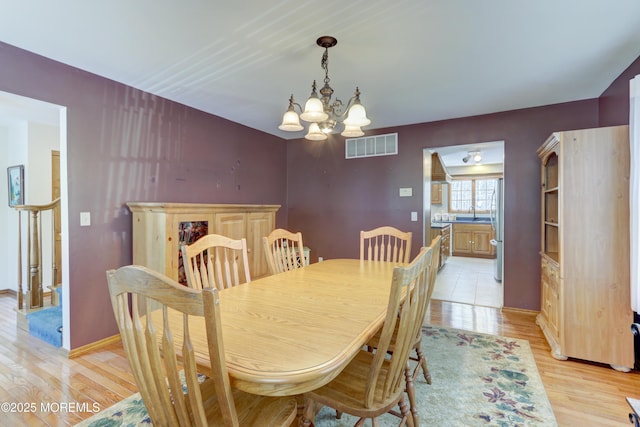 dining space featuring light hardwood / wood-style flooring and a notable chandelier