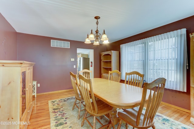 dining space with light wood-type flooring and a notable chandelier