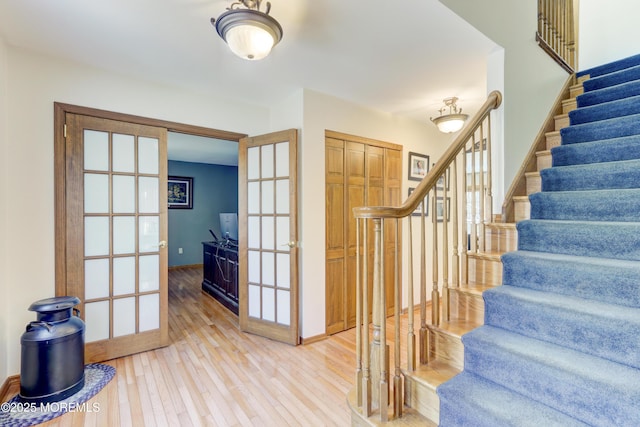 stairway featuring wood-type flooring and french doors