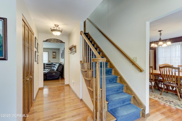 staircase with a notable chandelier and hardwood / wood-style flooring