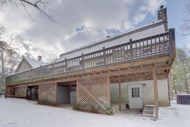 snow covered house with central air condition unit and a wooden deck