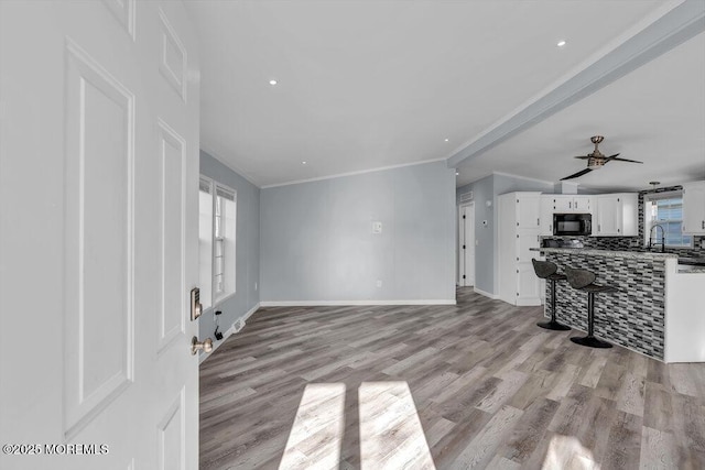 living room featuring ceiling fan, sink, light hardwood / wood-style flooring, and crown molding