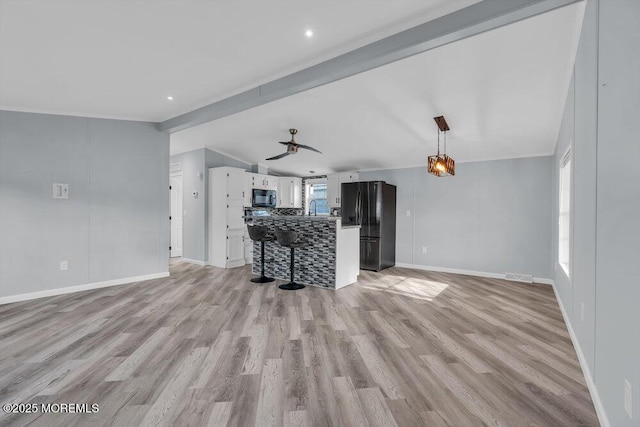 unfurnished living room with ceiling fan, a wealth of natural light, light hardwood / wood-style floors, and lofted ceiling with beams