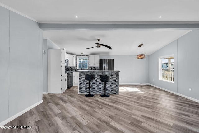 unfurnished living room featuring light wood-type flooring, ceiling fan, ornamental molding, and lofted ceiling