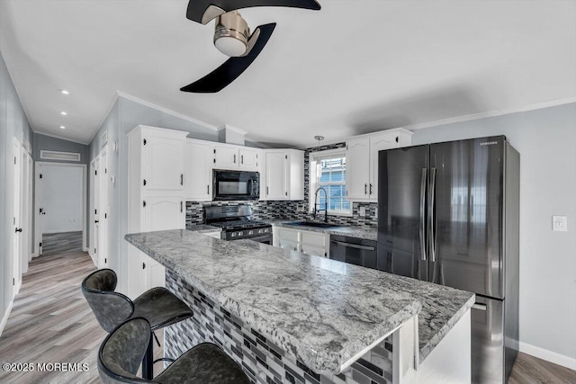 kitchen featuring black appliances, white cabinetry, decorative backsplash, sink, and vaulted ceiling