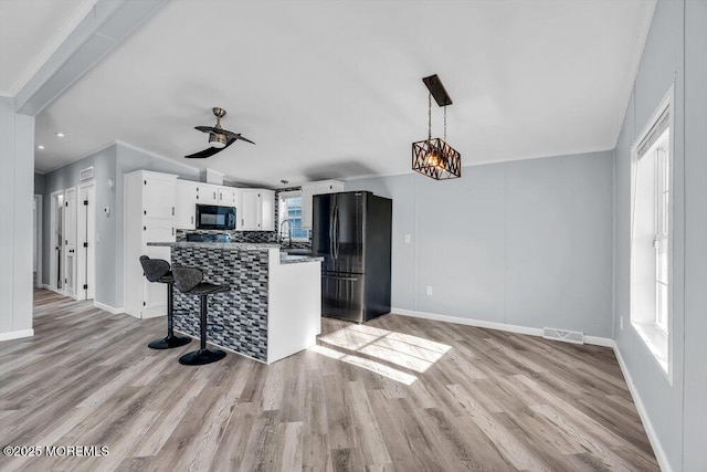 kitchen with black appliances, white cabinetry, plenty of natural light, and light hardwood / wood-style floors