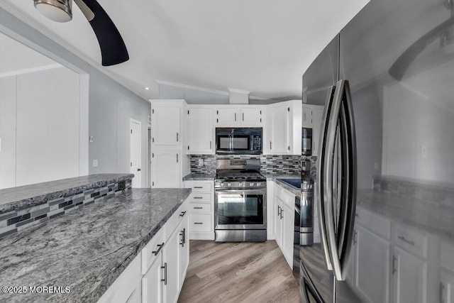 kitchen featuring lofted ceiling, white cabinetry, stainless steel appliances, tasteful backsplash, and dark stone countertops