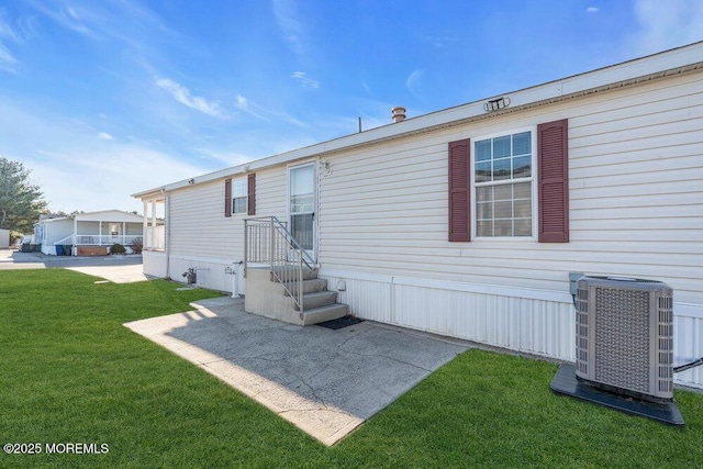 rear view of property featuring central AC unit, a yard, and a patio