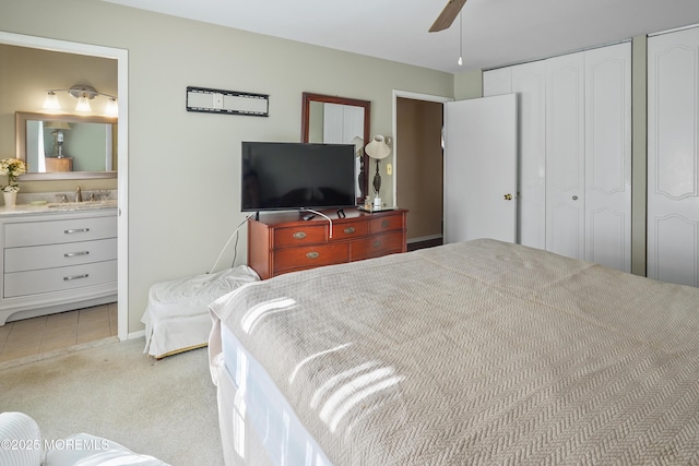 carpeted bedroom with multiple closets, ceiling fan, ensuite bathroom, and sink