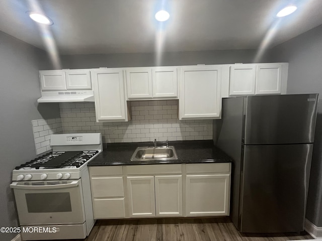 kitchen featuring sink, white cabinets, gas range gas stove, decorative backsplash, and stainless steel refrigerator