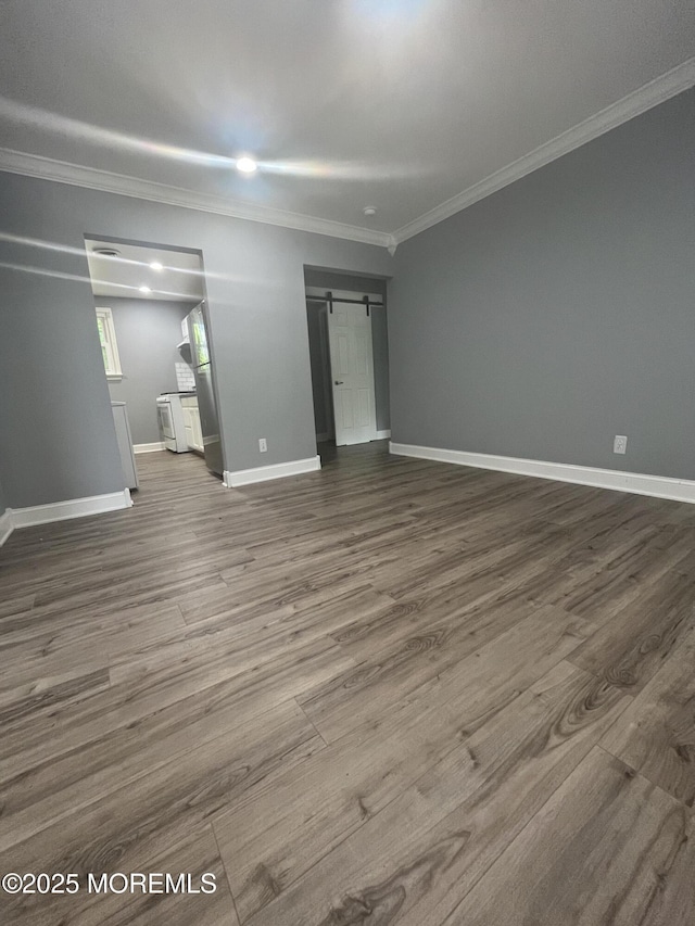 interior space featuring a barn door, ornamental molding, and wood-type flooring