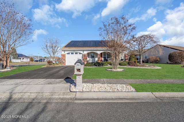 ranch-style home with a garage, a front yard, and solar panels