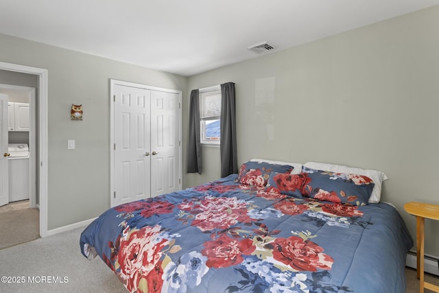 carpeted bedroom featuring a baseboard heating unit, washer / dryer, and a closet