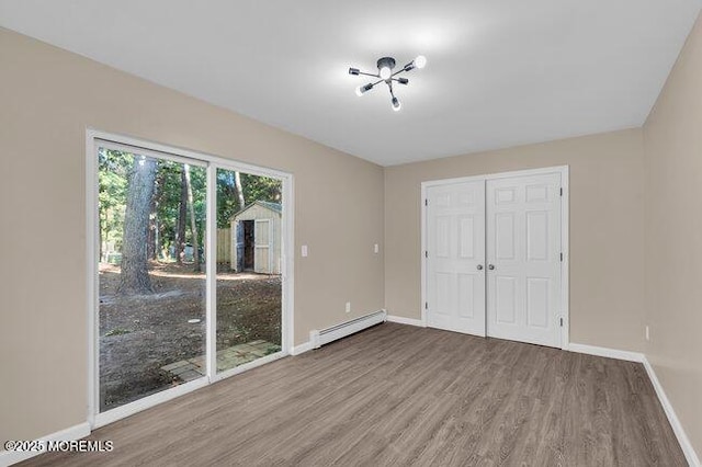 unfurnished bedroom featuring light wood-type flooring, a closet, and a baseboard radiator