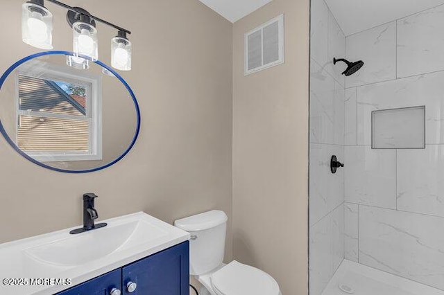 bathroom featuring toilet, vanity, and tiled shower