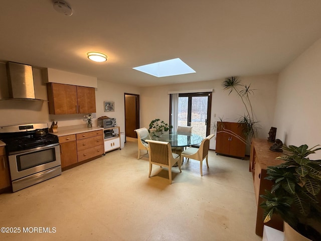 kitchen featuring wall chimney range hood, a skylight, and gas stove