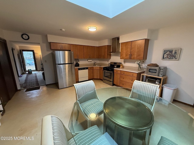 kitchen with sink, a skylight, wall chimney range hood, and appliances with stainless steel finishes