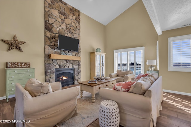 living room with high vaulted ceiling, a fireplace, hardwood / wood-style floors, and a textured ceiling