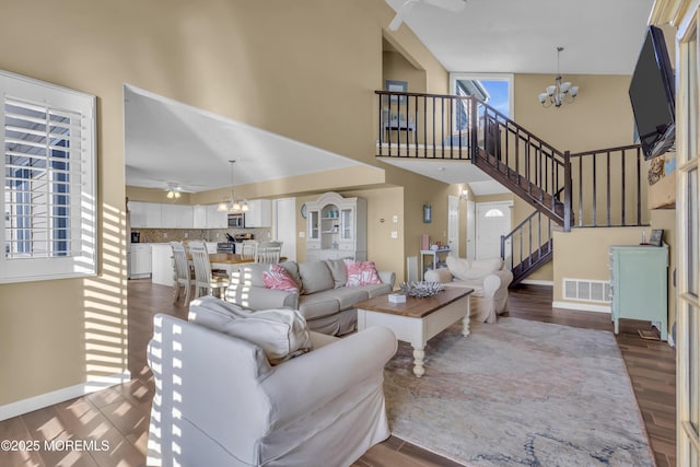 living room with hardwood / wood-style flooring, ceiling fan with notable chandelier, and a towering ceiling