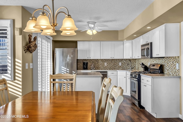 kitchen with white cabinetry, stainless steel appliances, decorative backsplash, a healthy amount of sunlight, and decorative light fixtures