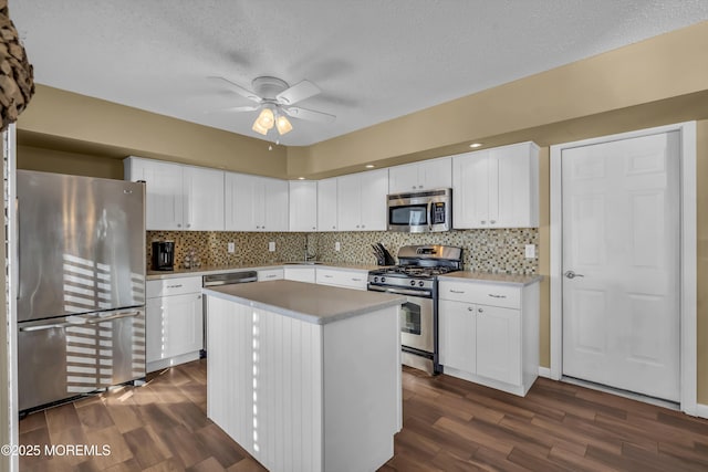 kitchen with stainless steel appliances, white cabinetry, a center island, and dark hardwood / wood-style flooring