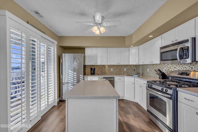 kitchen featuring sink, white cabinetry, tasteful backsplash, a center island, and appliances with stainless steel finishes