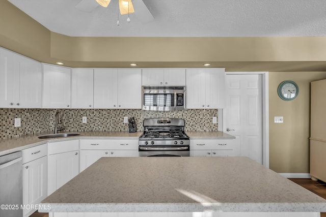 kitchen featuring appliances with stainless steel finishes, sink, a kitchen island, and white cabinets