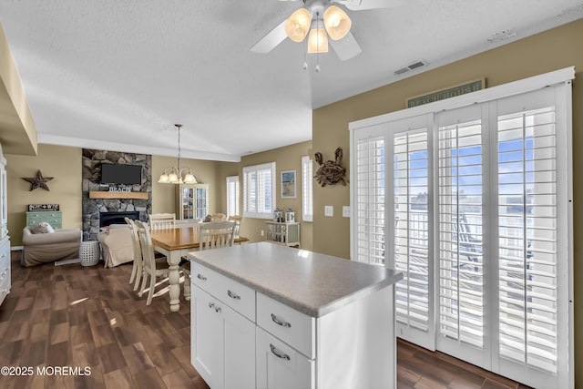 kitchen with a kitchen island, dark wood-type flooring, white cabinets, and a textured ceiling