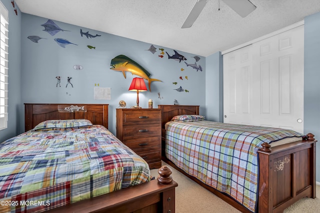 carpeted bedroom with ceiling fan, a closet, and a textured ceiling