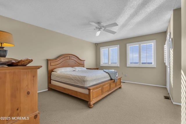 bedroom with ceiling fan, light colored carpet, and a textured ceiling