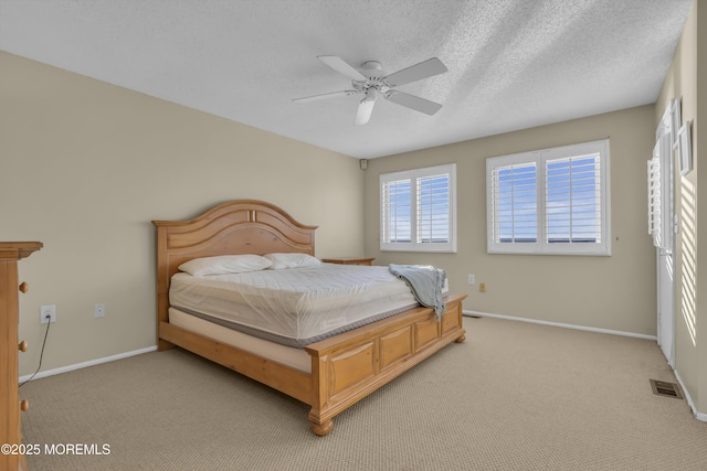 carpeted bedroom with ceiling fan and a textured ceiling