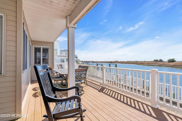 wooden terrace featuring outdoor dining area and a water view