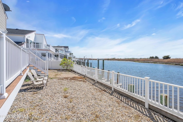view of yard with a fenced backyard, a water view, and a dock