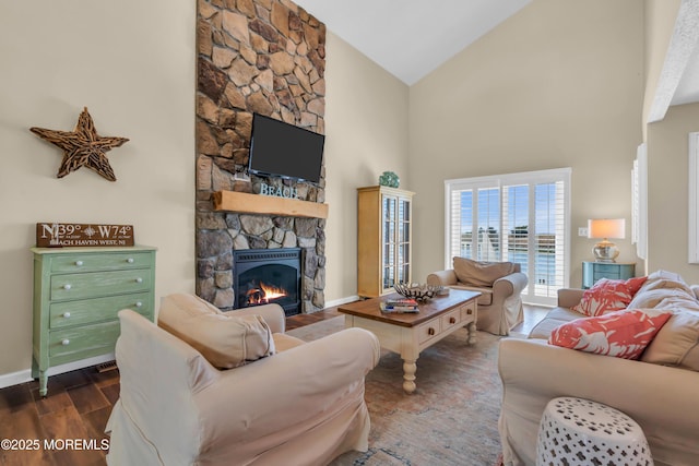 living room with high vaulted ceiling, dark wood-style floors, a stone fireplace, and baseboards