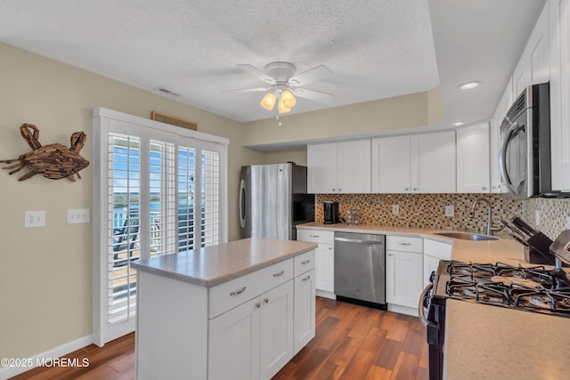 kitchen with wood finished floors, appliances with stainless steel finishes, a sink, and tasteful backsplash