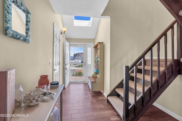 entryway featuring stairs, wood finish floors, baseboards, and vaulted ceiling with skylight
