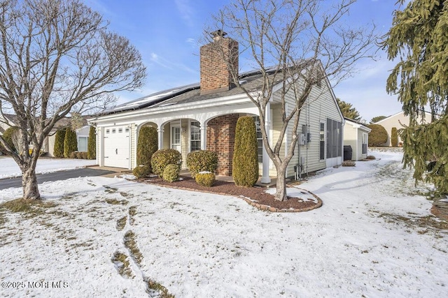 view of front of property with a garage, a porch, and solar panels