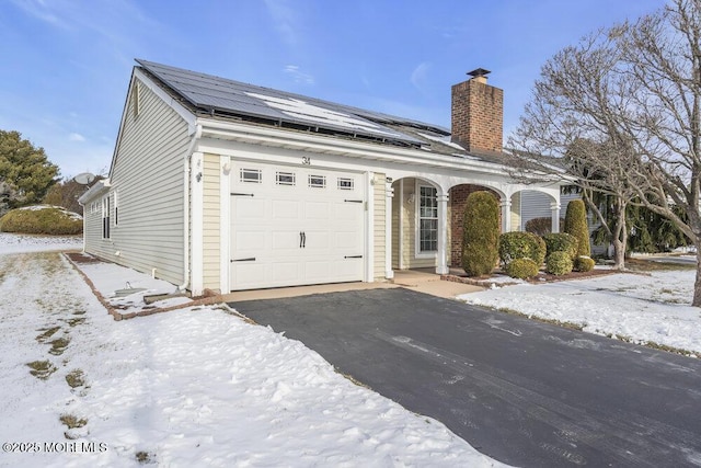 view of front of property with a garage and solar panels