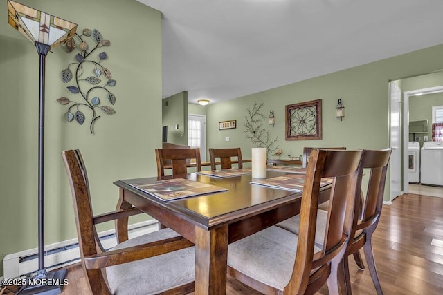 dining room with a baseboard heating unit, dark wood-type flooring, and washing machine and clothes dryer