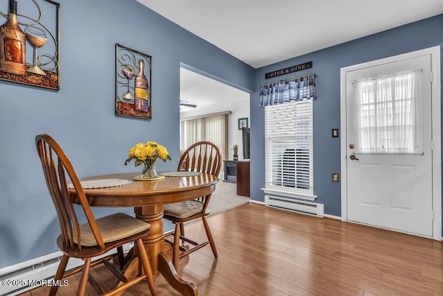 dining space with hardwood / wood-style flooring and baseboard heating