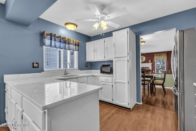 kitchen featuring white cabinets, sink, stainless steel fridge, and kitchen peninsula