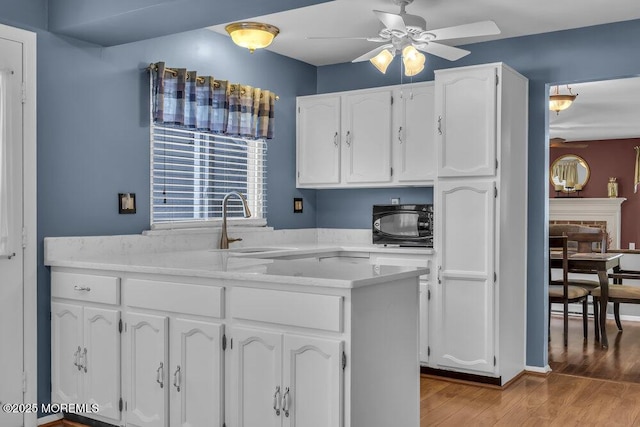 kitchen with sink, ceiling fan, white cabinetry, kitchen peninsula, and light wood-type flooring