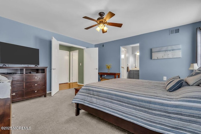 carpeted bedroom with ensuite bathroom and ceiling fan