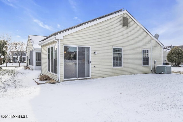 snow covered house featuring central AC unit