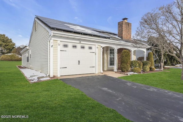 view of front of house featuring a garage, a front lawn, and solar panels