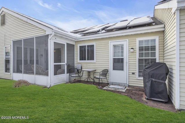 rear view of house with a lawn, a sunroom, and solar panels