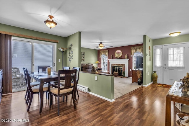 dining space featuring a brick fireplace, wood-type flooring, and ceiling fan