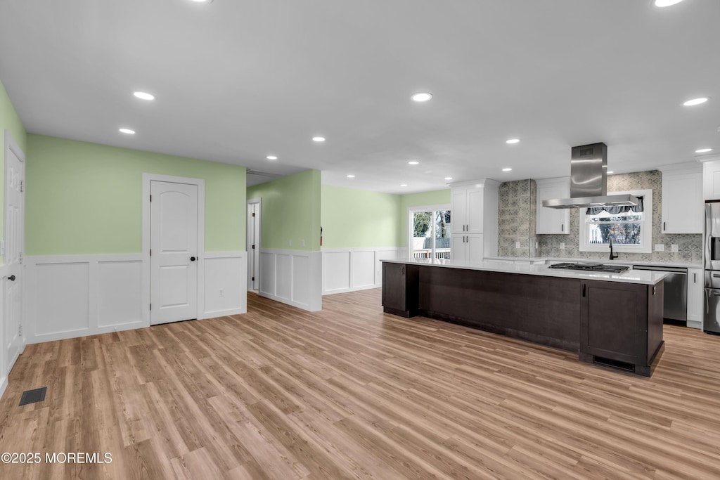 kitchen featuring backsplash, island exhaust hood, a center island, and white cabinets