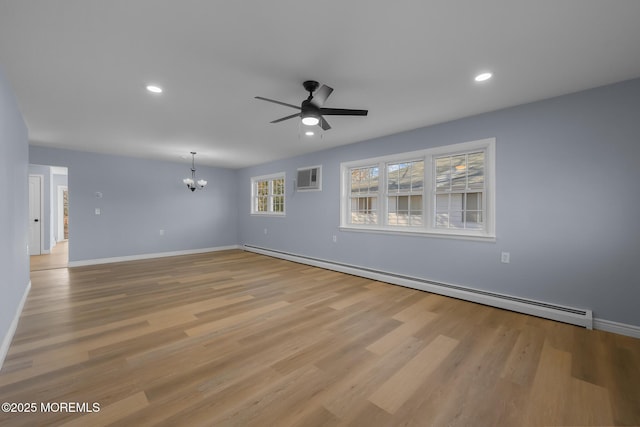 unfurnished room with light hardwood / wood-style floors, a baseboard heating unit, an AC wall unit, and ceiling fan with notable chandelier